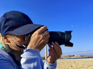 A woman photographer takes a picture on the beach