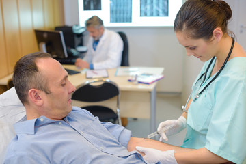 nurse injecting mature male patient