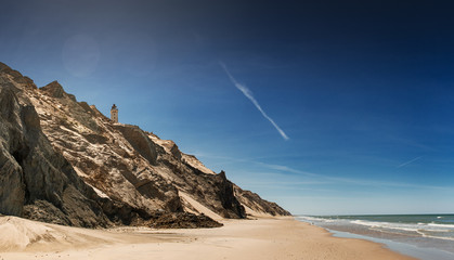 Sand cliffs and sand dunes with the famous lighthouse seen from the danish beach. Rubjerg Knude...