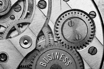 Background with the inscription BUSINESS. Black white background with metal cogwheels clockwork....