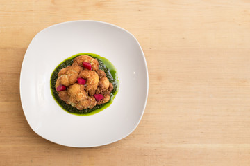 A plate of fried cauliflower on pesto with pickled carrots.