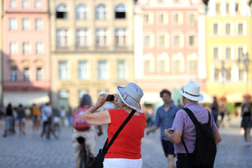 Stara kobieta i mężczyzna robią zdjęcia telefonem komurkowym na rynku Wrocławskim.