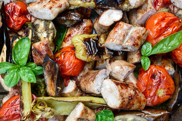 Juicy sausages and grilled vegetables in a glass bowl. Dinner outdoors. Garden party. The top view. Close up