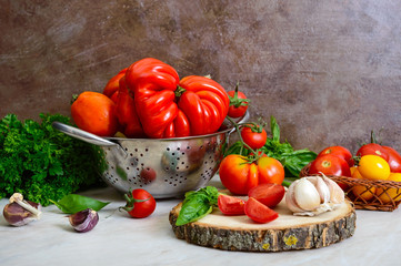 Ripe juicy tomatoes of different varieties, green fragrant basil, garlic on the table. Italian Cuisine.