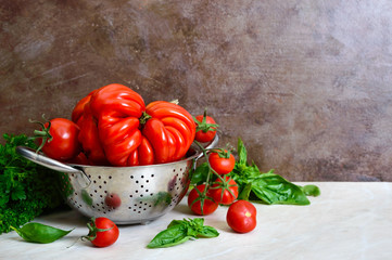Ripe juicy tomatoes of different varieties, green fragrant basil on the table. Italian Cuisine.
