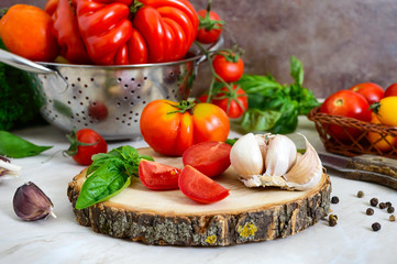 Ripe juicy tomatoes, green fragrant basil, garlic, pepper on the table. Ingredients for cooking Italian cuisine.