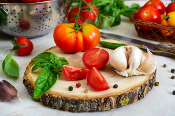 Ripe juicy tomatoes, green fragrant basil, garlic, pepper on the table. Ingredients for cooking...