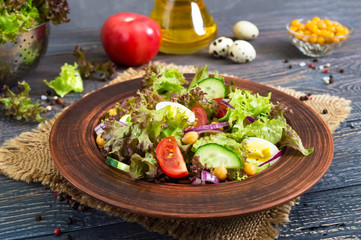 Tasty vegetarian salad with fresh vegetables, herbs, quail eggs, chickpeas in a clay bowl on a wooden table. Proper nutrition. Healthy food.