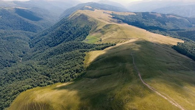 Aerial shot of a Carpathian range with a snaky country road in summer