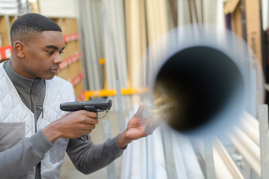 Worker In Distribution Warehouse With Handheld Barcode Scanner