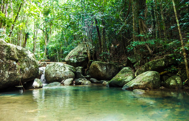 Naklejka na ściany i meble Jungle stream flowing into waterfalls & pools, with surrounding rain forest and large rocks. Taken on a bright day at Paeng Waterfall, Ko Pha Ngan, Thailand.