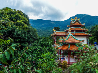 Beautiful view of the Goddess of Mercy Shrine Temple in Chaloklum, Ko Pha Ngan, Thailand. Showing the ornate, orange roof of the main pagoda and the surrounding jungle. Taken on a stormy day.