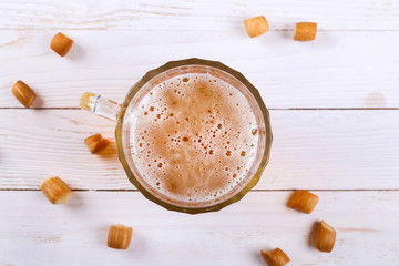 Lager beer mug and snacks on white wooden table.