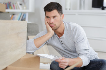frustrated man holding instructions for assembling furniture