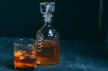 scotch whisky in old fashion glass and decanter with smoking cigar in ashtray on gray concrete background