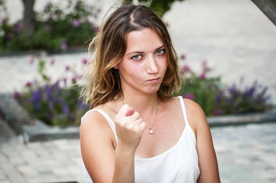 Young and sexy Caucasian girl showing a fig sign, a mildly obscene gesture meaning a negative answer, denial to a request. Two fingers and a thumb. #MeToo Firm NO to street sexual harassment.