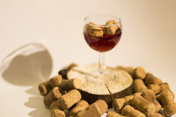 Empty glass of wine with wine stoppers (cork) inside on a white
