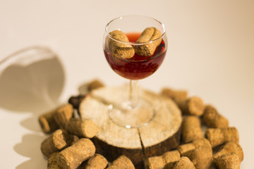 Empty glass of wine with wine stoppers (cork) inside on a white
