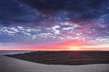 Fototapeta na wymiar Danish coastline with sand dunes landscape at a dramatic colorful dawn morning sunrise with the ocean. Rubjerg Knude Lighthouse, Lønstrup in North Jutland in Denmark, Skagerrak, North Sea