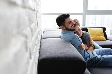 Young Couple Hugging and Kissing on Sofa