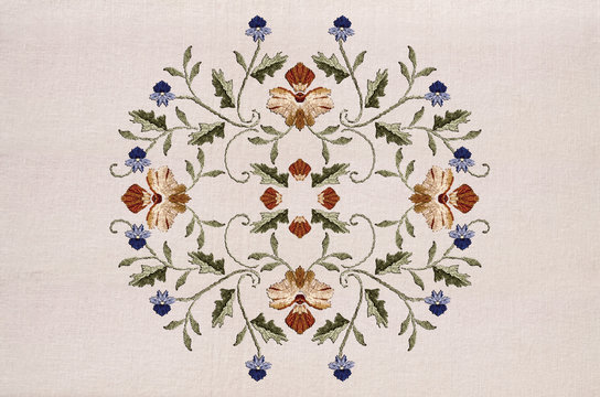 Oval pattern for embroidery  of red-yellow flower and blue flowers on twisted stems with leaves on cotton fabric


