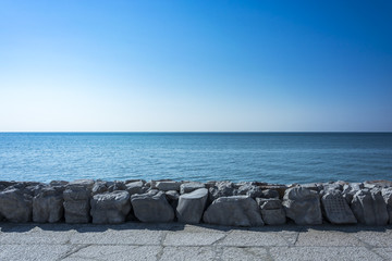 Sea view from a stony beach. Exact horizontal horizon. Blue sea level and strongly enlightened...