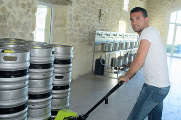 portrait of manufacturer carrying kegs in brewery