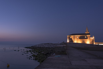 Enlightened church and tower "Santuario della Madonna dell'Angelo" in the town of Caorle on the coast at night.