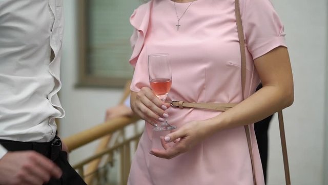 Woman in pink dress with glass of sparkling wine at the party indoors