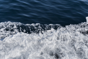 Flying sea water in the sea. White foam of sea water. Dark deepness in the sea.
