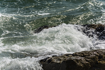 Small ocean sea waves on stone beach. Background wallpaper picture with roaring waves.