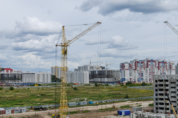 Construction crane against the background of houses under construction. Work at the construction site