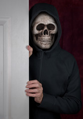Halloween theme of stalker with skull mask entering a home