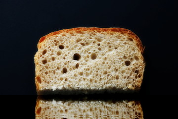 slice of rye bread on a dark background reflected in the water. God grant us our daily bread.