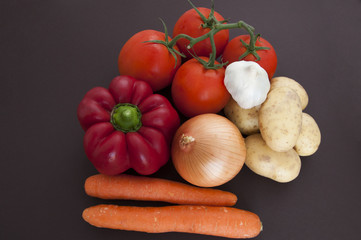 vegetables on black, tomatoes, peppers, onions, garlic, potatoes, carrots