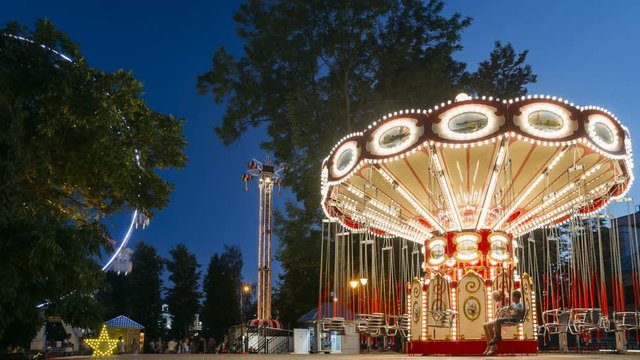 Brightly Illuminated Rotating High Speed Carousel Merry-Go-Round. Summer Evening In City Amusement Park