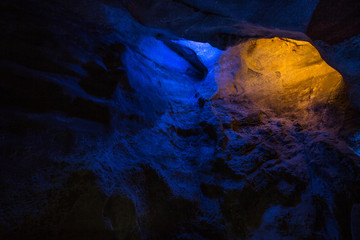 Abstract cave interior chamber photograph - colored lights, bumpy rock surfaces and exotic rock...