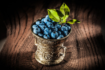Juicy blueberries in vintage metal bowl on grunge board