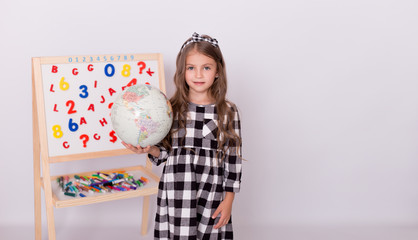  Caucasian schoolgirl   in cute dress is holding a globe