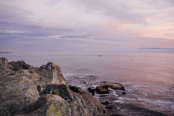 Fototapeta na wymiar Ocean view at sunset with purple sky and rocks