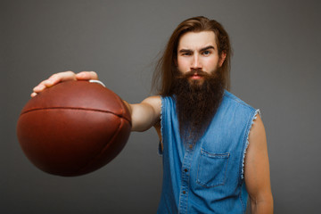 Brutal man with a beard holds a rugby ball in his hand