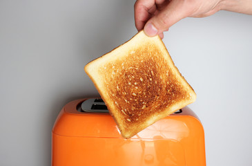 hand toast and orange toaster on a light background