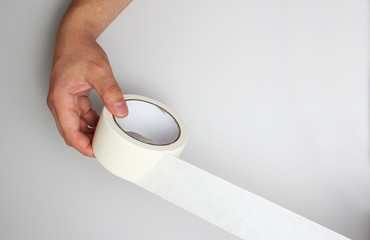 hand and Scotch tape on a gray background