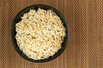 Instant noodles in a black bowl on Japanese mat