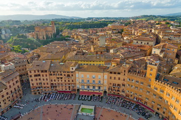 Fototapeta na wymiar Aerial and top view scenery of old ancient Tuscany region town, Piazza del Campo and medieval brick buildings with green range mountain landscape background in Siena, Italy 