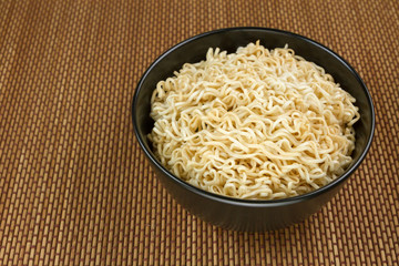 Instant noodles in a black bowl on Japanese mat