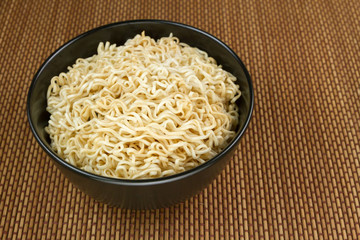 Instant noodles in a black bowl on Japanese mat
