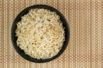 Instant noodles in a black bowl on Japanese mat