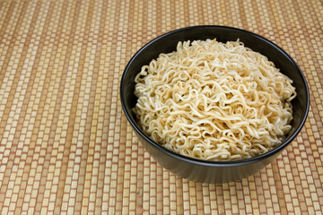 Instant noodles in a black bowl on Japanese mat