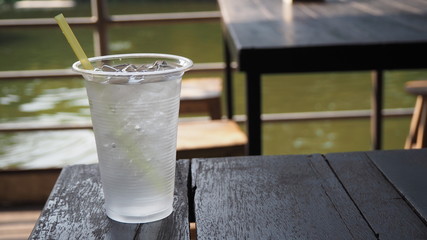 Image of pure water with ice in plastic glass lay on old wood table. Ice in a glass made of plastic.